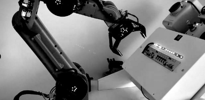 Close-up of robotic arms with claw-like grippers in an industrial automation setting.