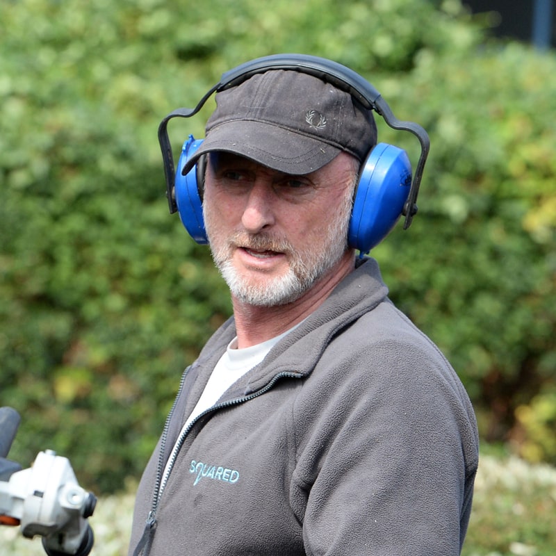 Man working outdoors with ear protection and safety gear near equipment setup.