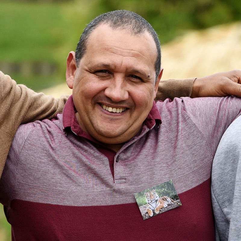 A middle-aged man in a red and grey polo shirt with a casual smile and photo.