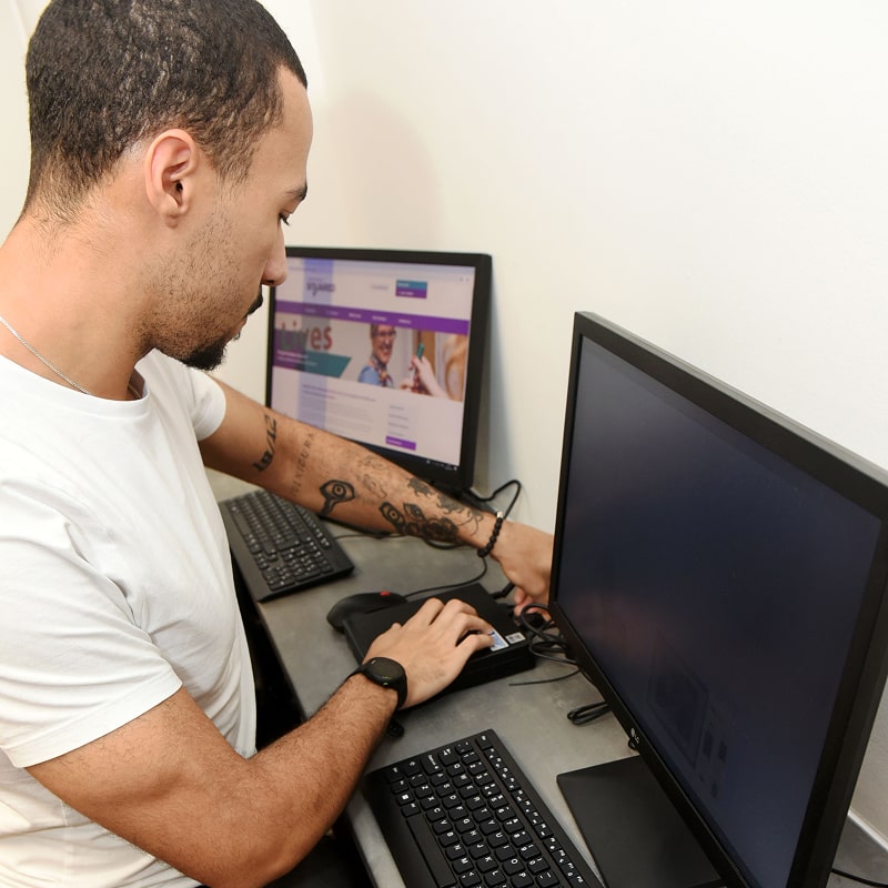 Busy professional works efficiently on two computer monitors with keyboard and ergonomic mouse.