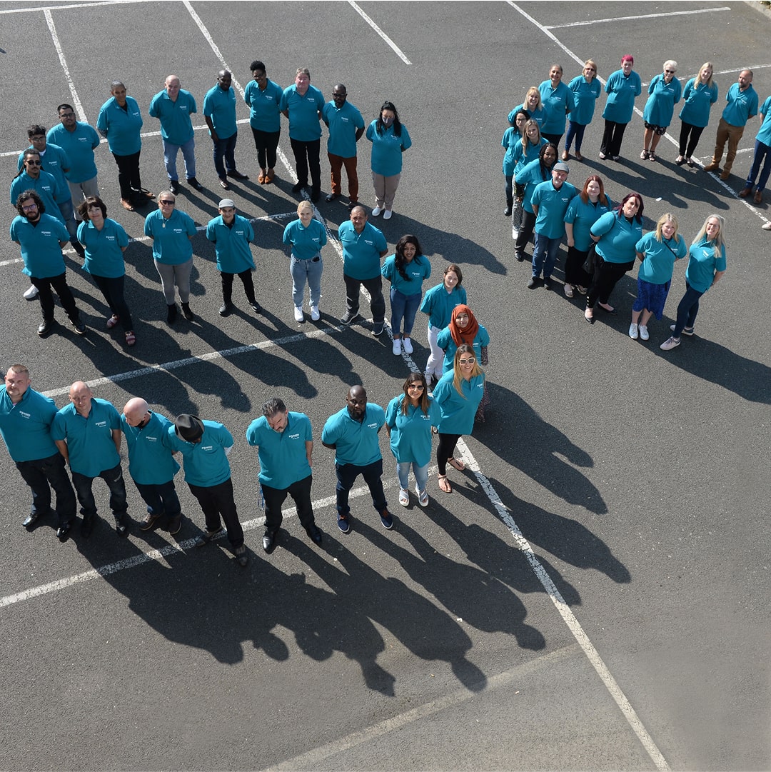 Group of diverse people wearing identical blue shirts form a massive human number nine formation.