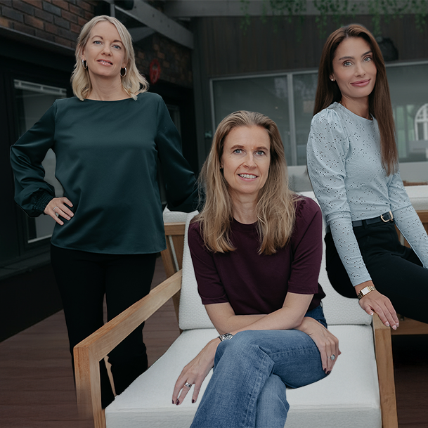 Kvinna med långt blont hår som ler och håller en whiteboard-pennor framför en whiteboard med ordet 'MÅH!' skrivet på den.