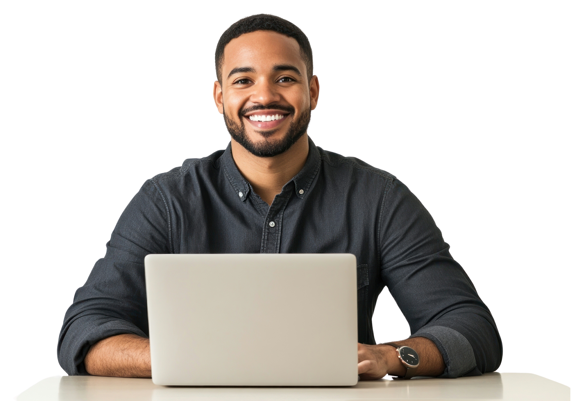 Smiling man with a beard wearing a dark button-up shirt sitting at a table with a laptop.