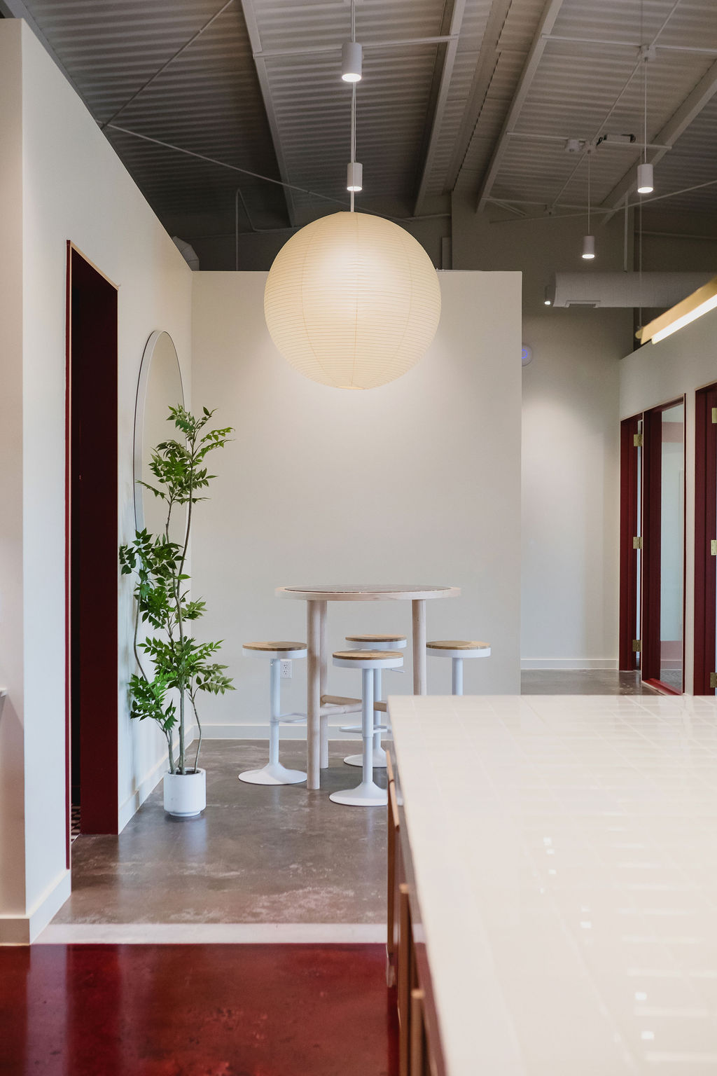 Entry and reception at Junto House with a Noguchi pendant and exposed industrial ceiling.