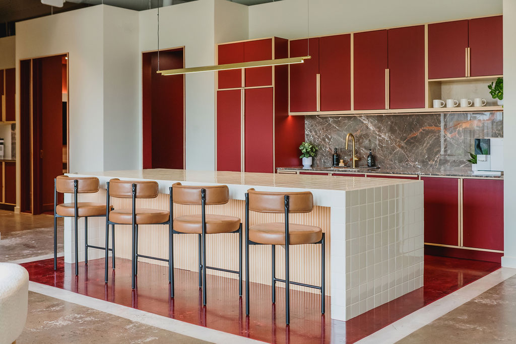 Kitchen bar at Junto House with four stools and a brass linear pendant over a stone counter.
