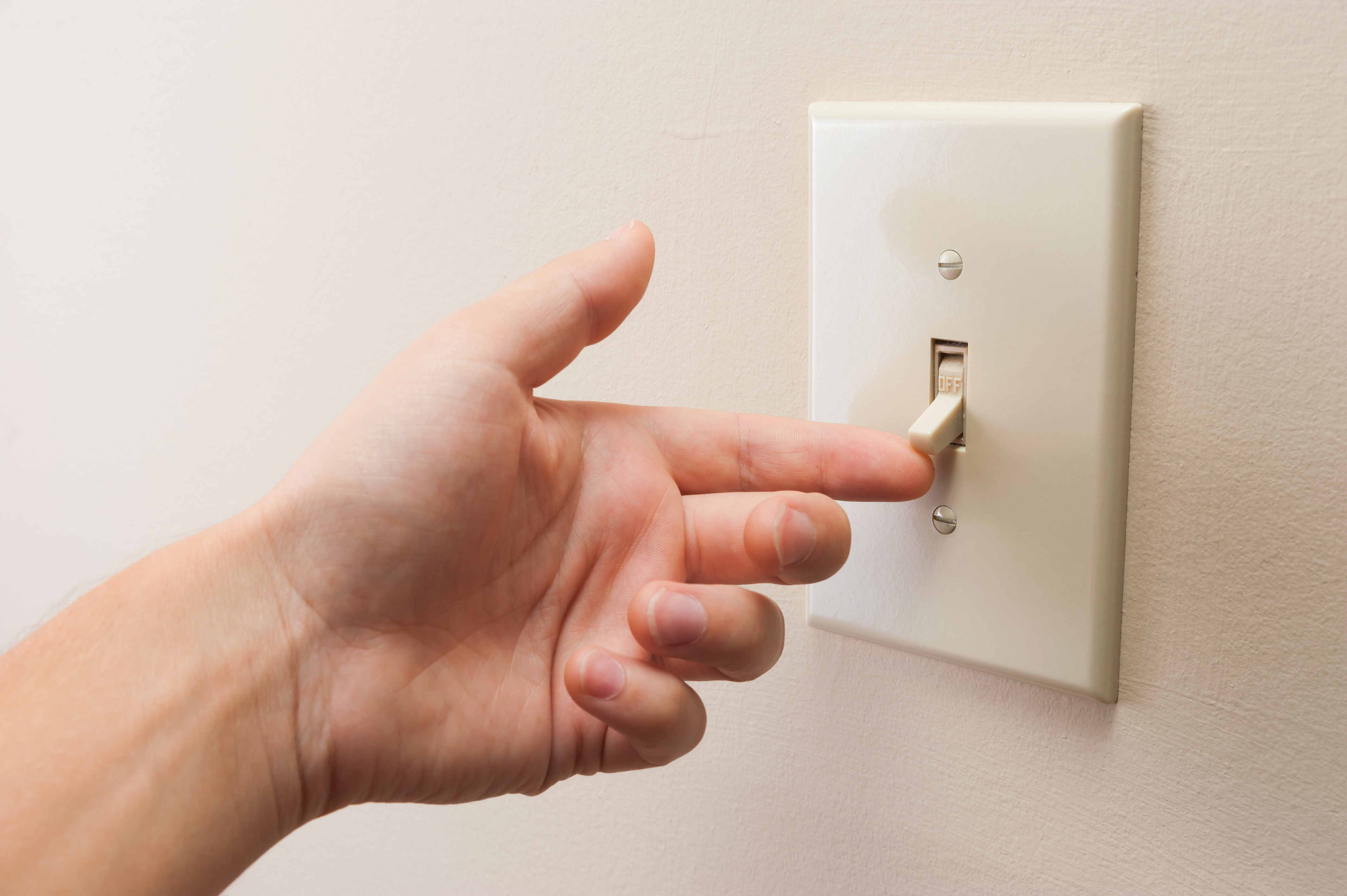 A hand turning on a light switch