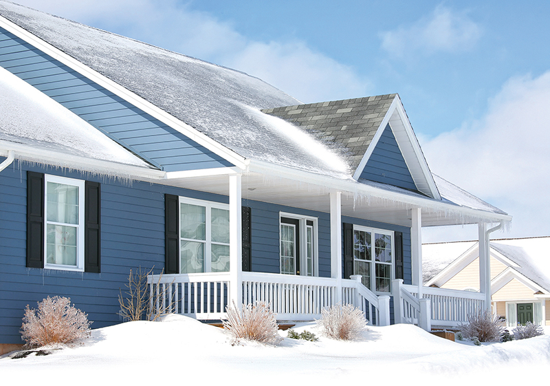 The front of a blue house with snow in the yard