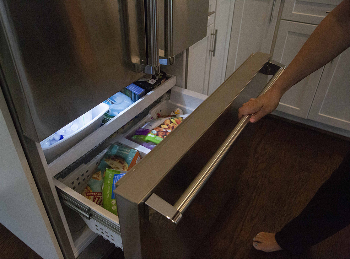 Someone opening a bottom drawer freezer