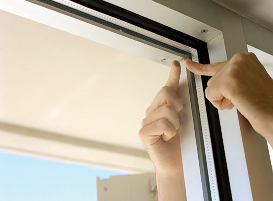 A hand checking the seal on a window