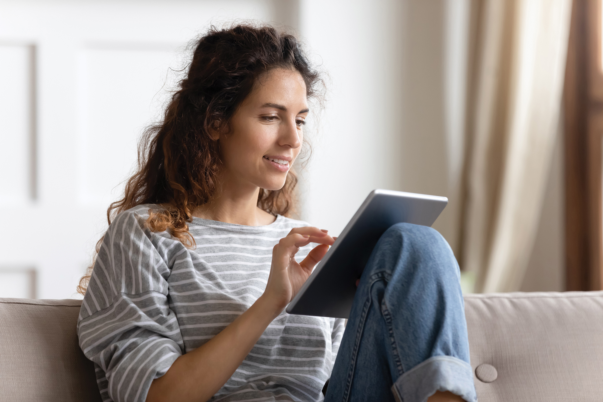 Woman sitting on couch working on a digital tablet