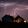 A home at night during a storm with lightning above it