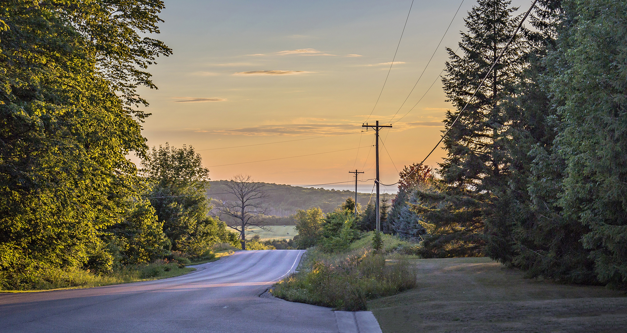 a 69-kV line along a road at sunset