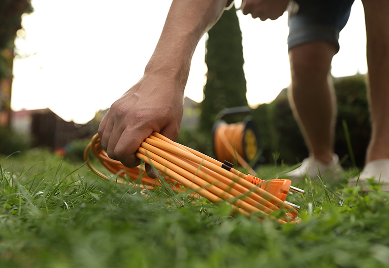 A person picking up a rolled up extension cord