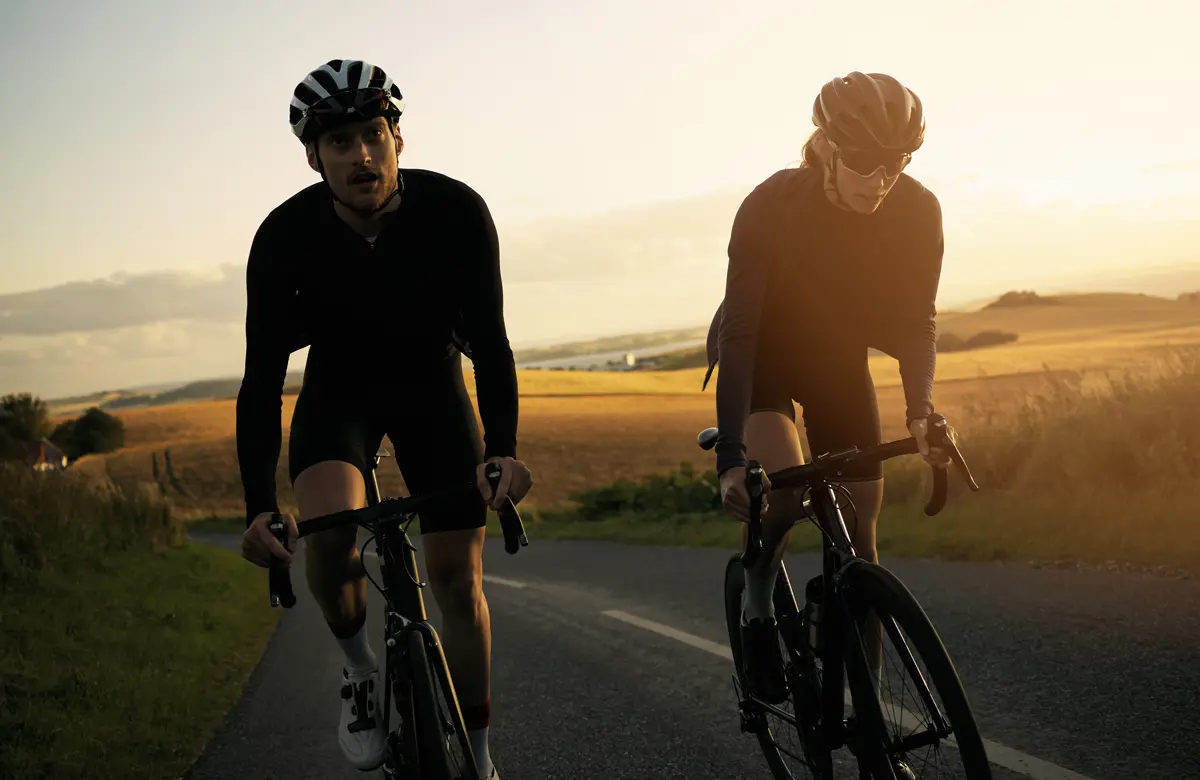 Two cyclists riding on a country road at golden hour.