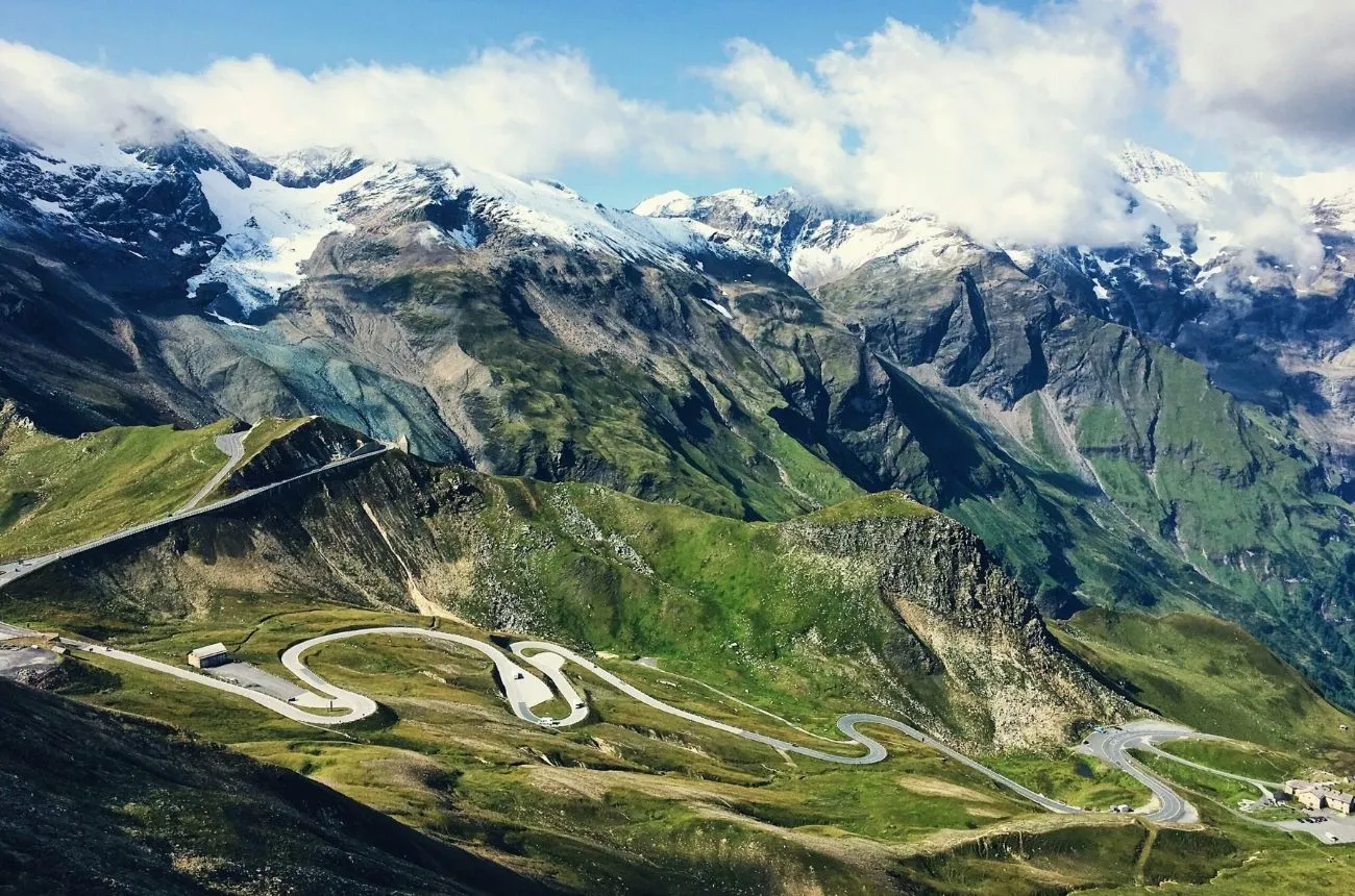 Three cyclists smiling and riding together on a mountain road — group cycling coaching for accountability and results