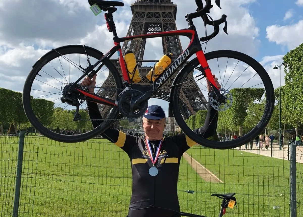 Middle-aged cyclist celebrates Paris cycling event completion after training plan