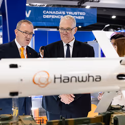 Des cadres de l'industrie de la défense discutent de la technologie de prochaine génération à côté d'un écran d'avion.