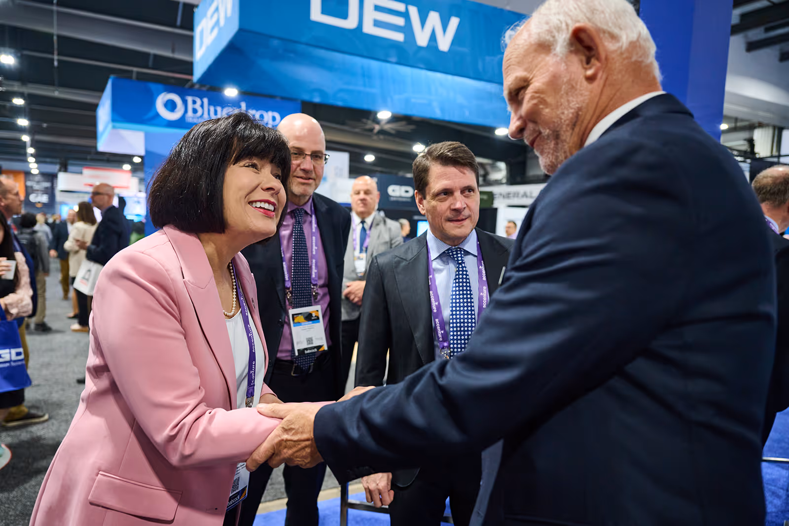 Business professionals networking and shaking hands at a defence industry event.