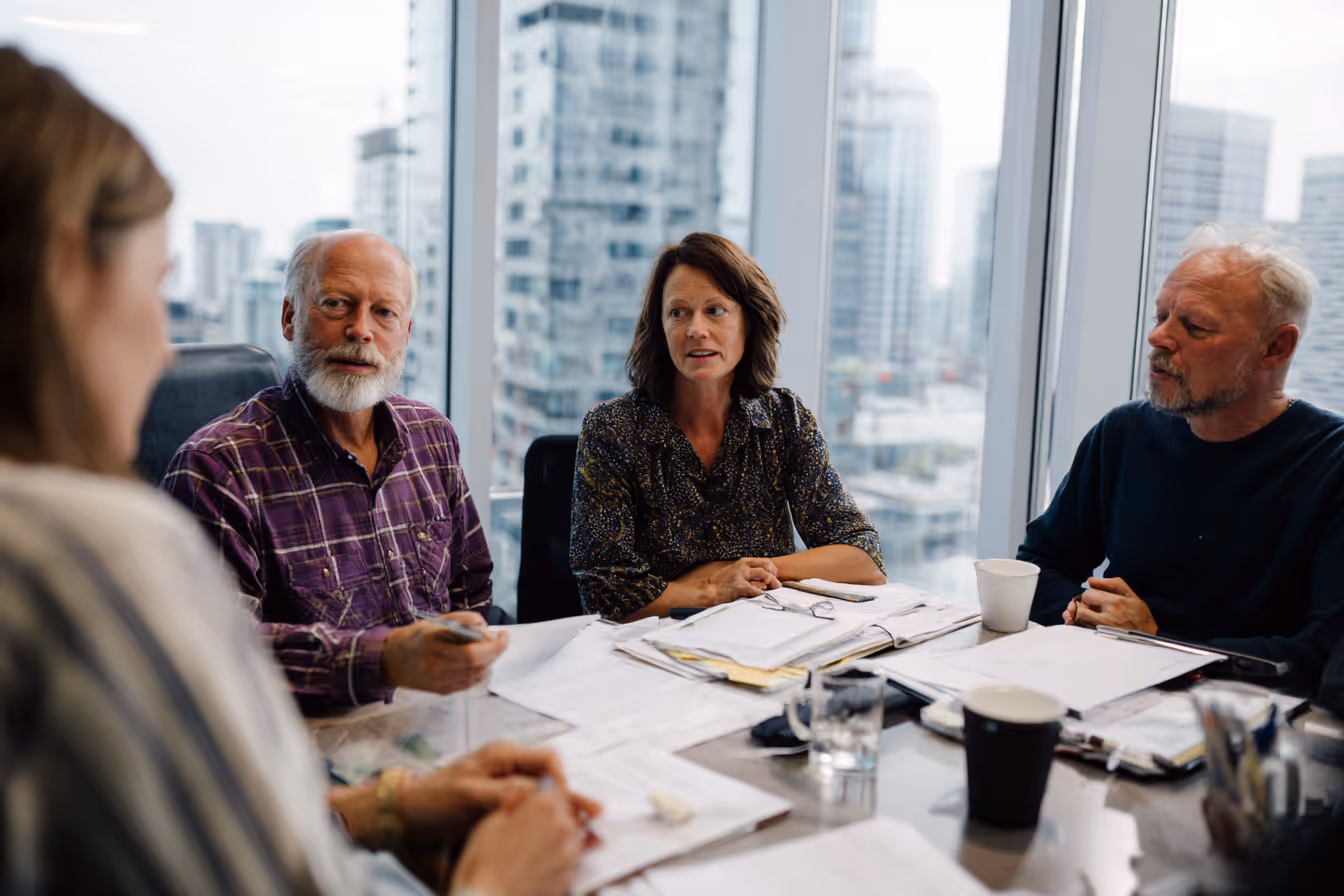 Group of professionals meeting in a modern boardroom with large windows overlooking the city.
