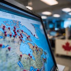 Large digital screen displaying a world map with data overlays used for strategic planning discussions.