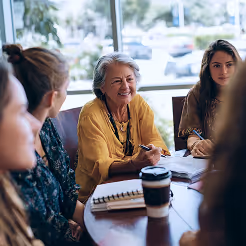 Women in defence and security professionals talking around a table during a mentorship session.