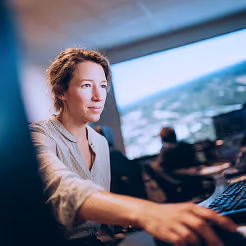 Woman operating a simulation control panel during a hands-on defence technology training session.