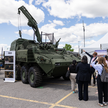 Defence industry executives discussing next-generation technology beside an aircraft display.