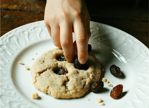 Hand som plockar russin ur en kaka på en vit tallrik