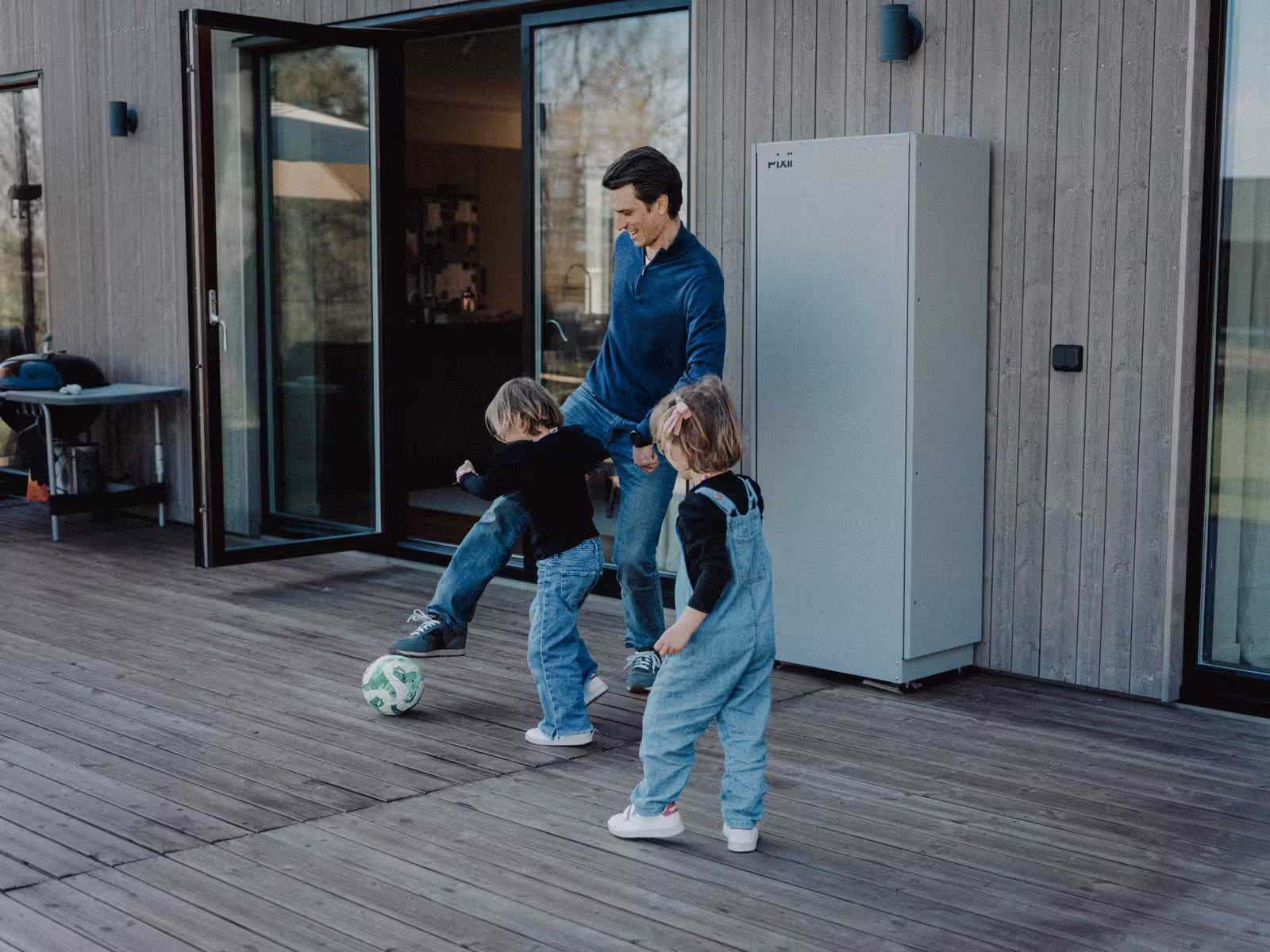 En familj som leker utomhus bredvid ett hembatteri