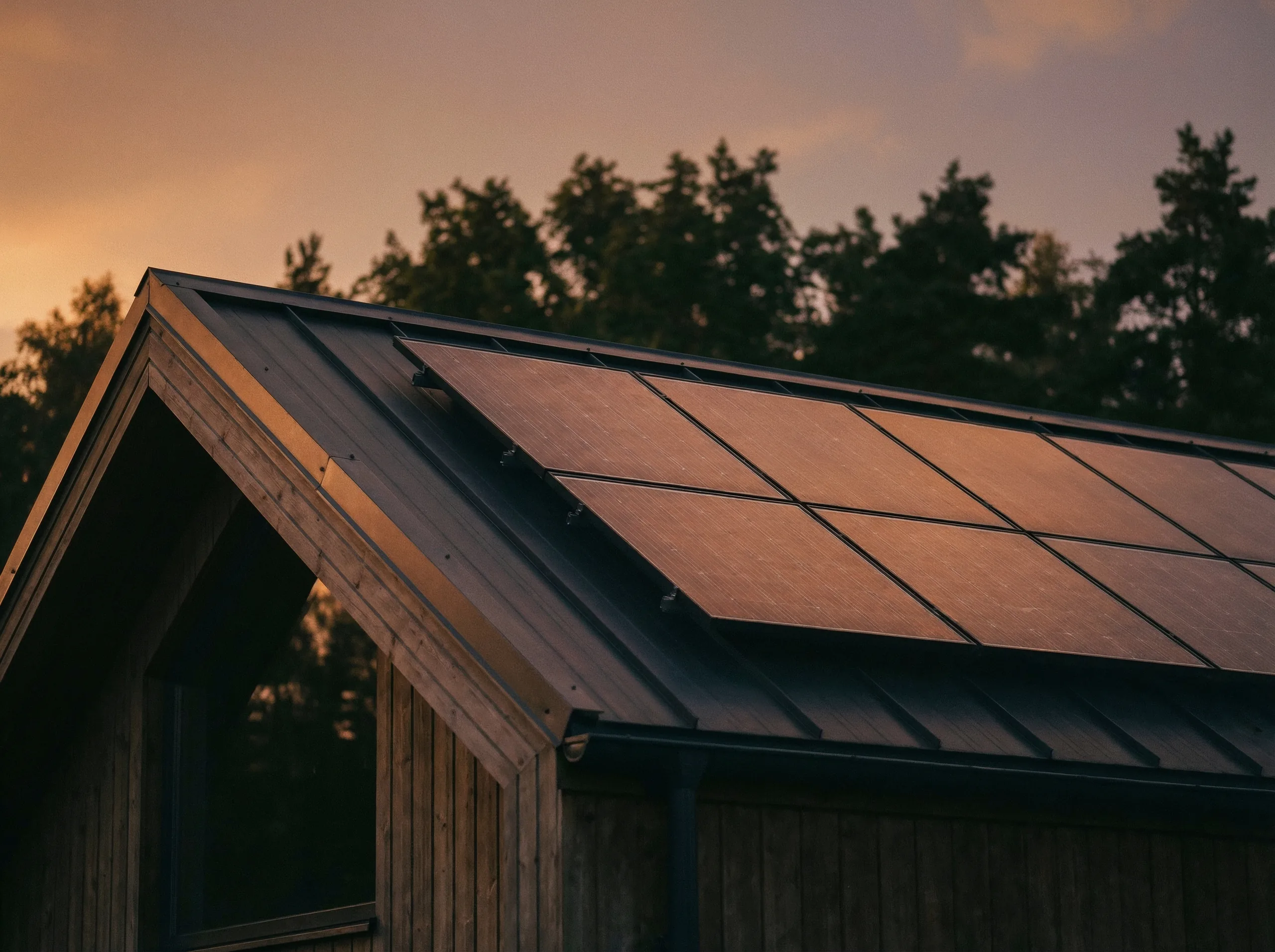 Solpaneler på taket till ett trähus i solnedgången
