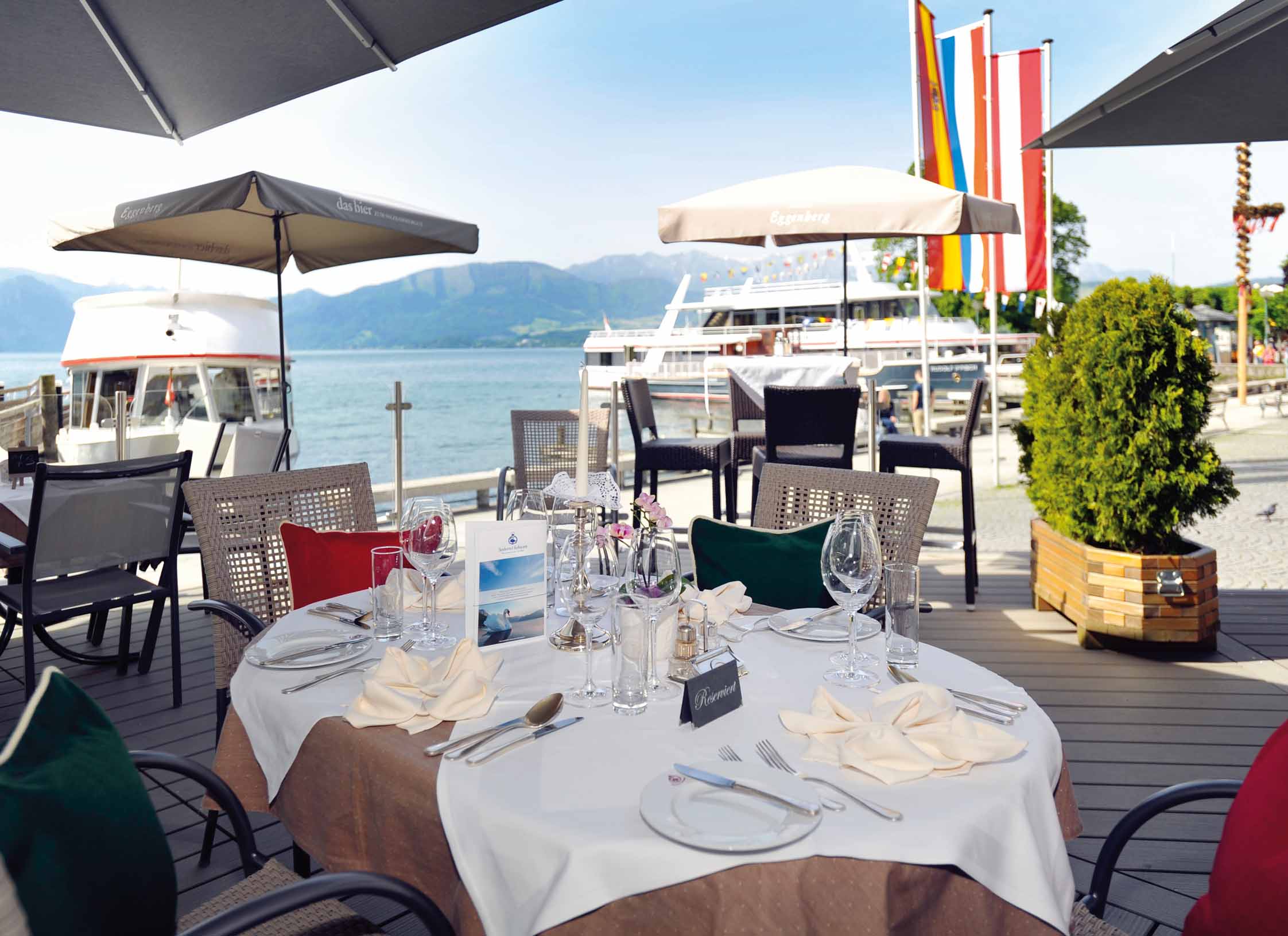 Ein runder Tisch steht auf einer Terasse, direkt vor einem See