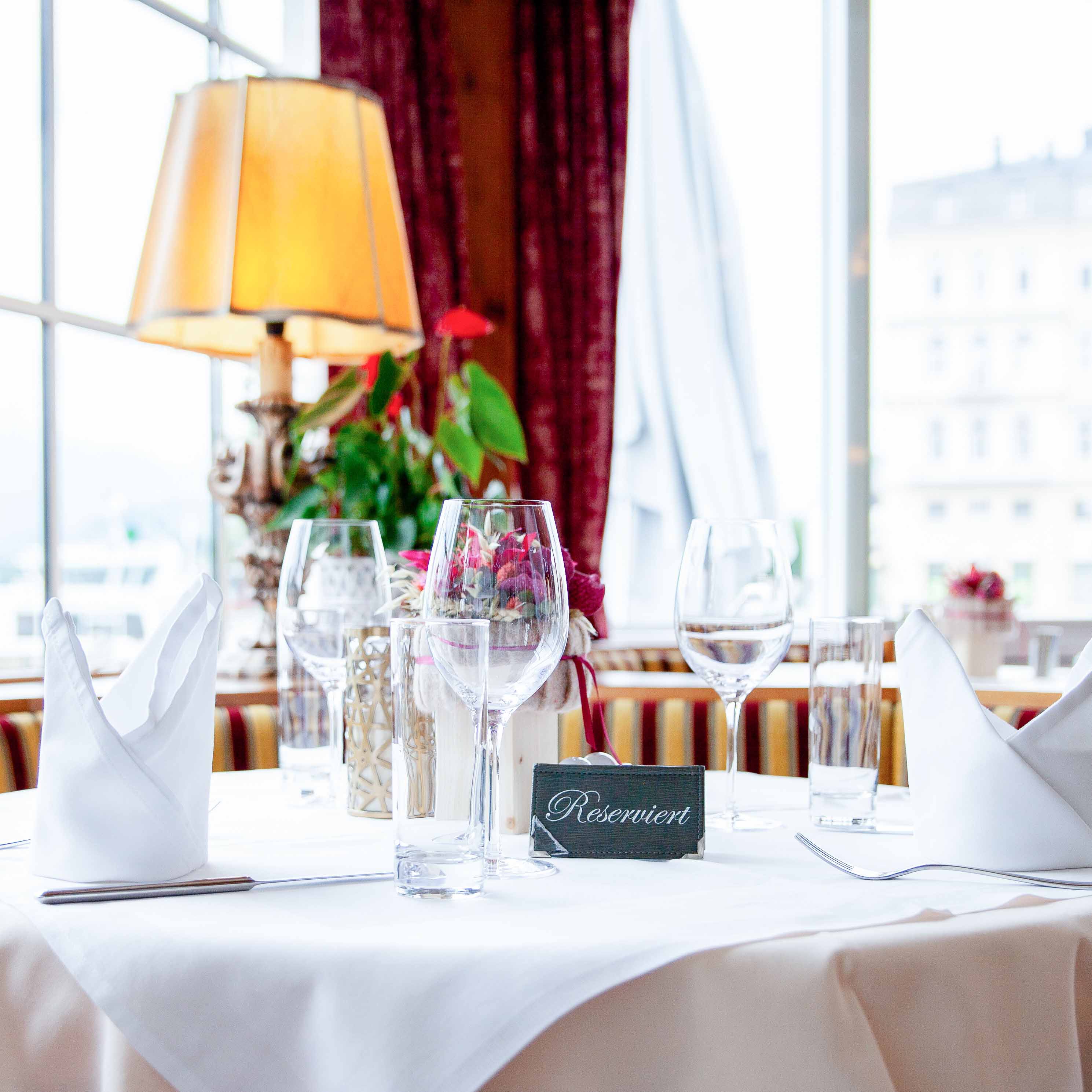 Eleganter Tisch in einem Restaurant mit weißer Tischdecke, gefalteten weißen Servietten, Weingläsern und einem Schild mit der Aufschrift 'Reserviert'.