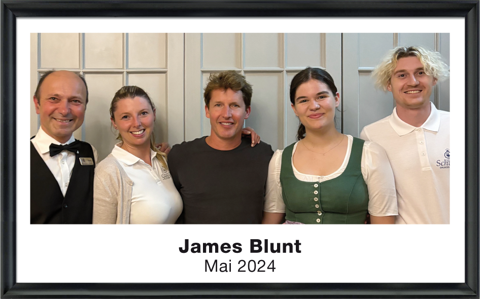 Fünf Personen lächeln vor einer grauen Paneelwand, darunter James Blunt Mitte Mai 2024.
