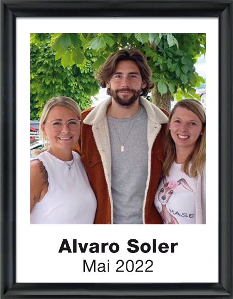 Alvaro Soler mit zwei lächelnden Frauen vor grünen Bäumen, Beschriftung darunter: Alvaro Soler Mai 2022.