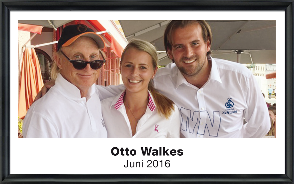 Drei Menschen, zwei Männer und eine Frau, lächeln in die Kamera unter einem Sonnenschirm, aufgenommen im Juni 2016.