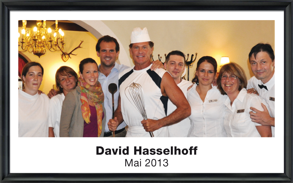 David Hasselhoff in Kochkleidung mit Kochlöffel und Schneebesen, umgeben von acht lächelnden Menschen in einem Restaurant, Mai 2013.