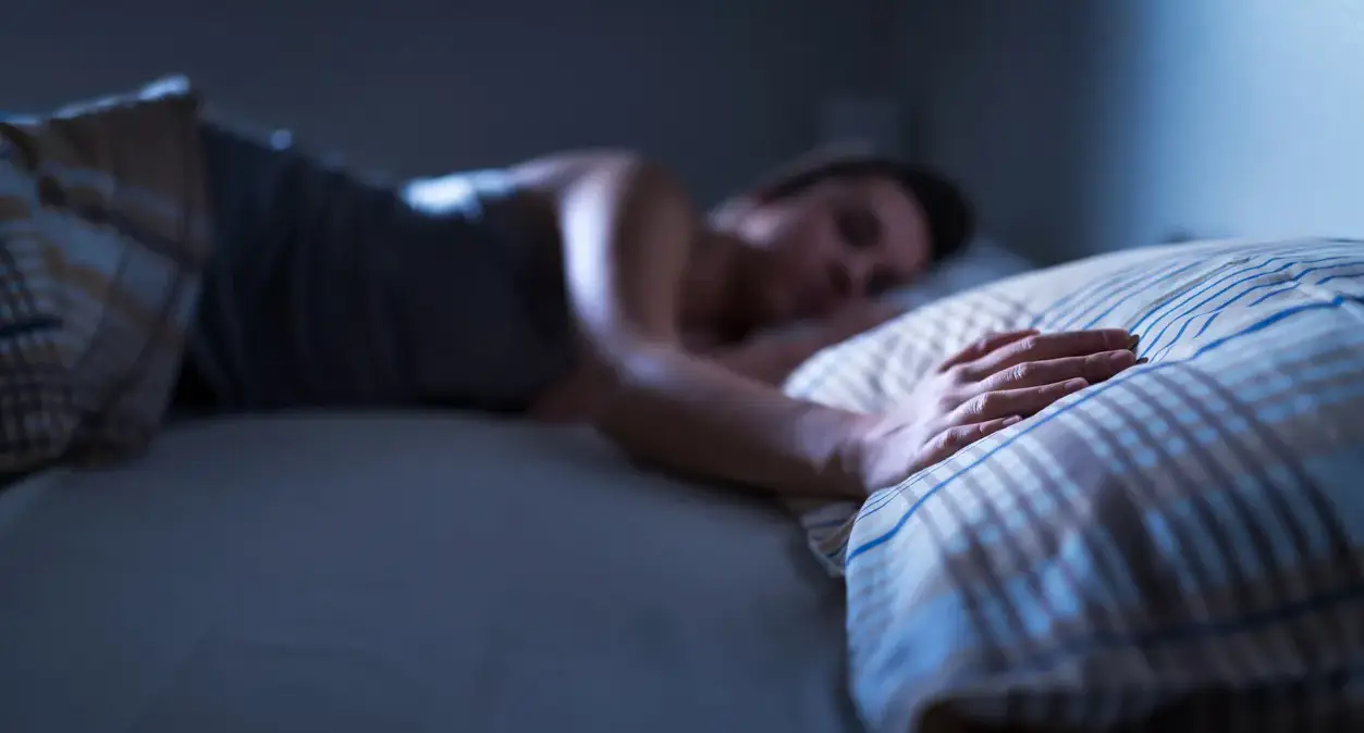 Person waking up at night with a numb, tingling arm and rubbing their hand for relief