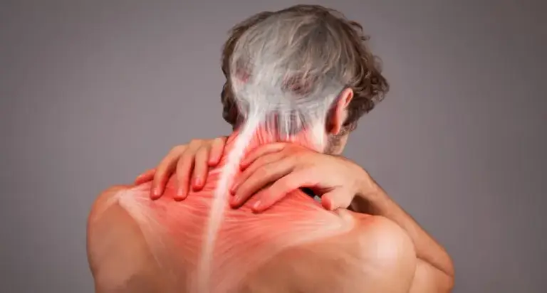 Adult holding the lower back with radiating leg pain, a common sign of a pinched nerve in the lumbar spine