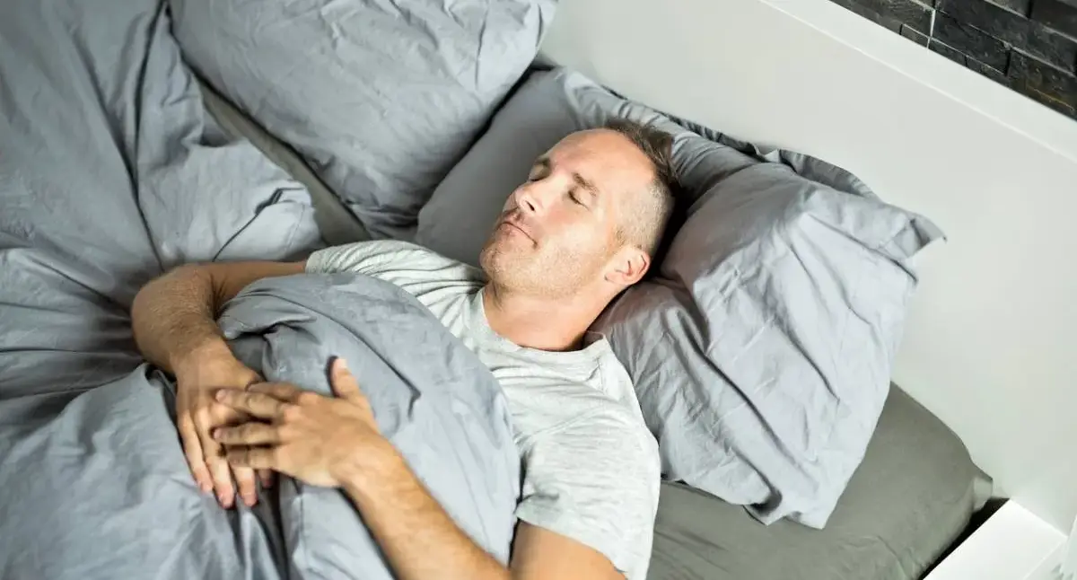 Person resting on their back with pillows supporting the head, neck, and knees after spine surgery