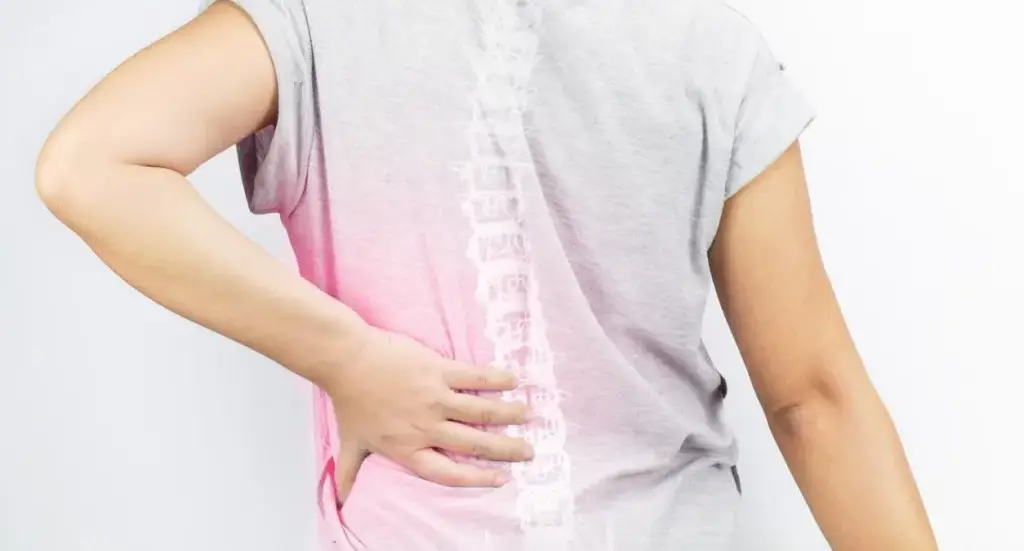 Person holding their lower back in discomfort, a possible early sign of spinal osteoarthritis