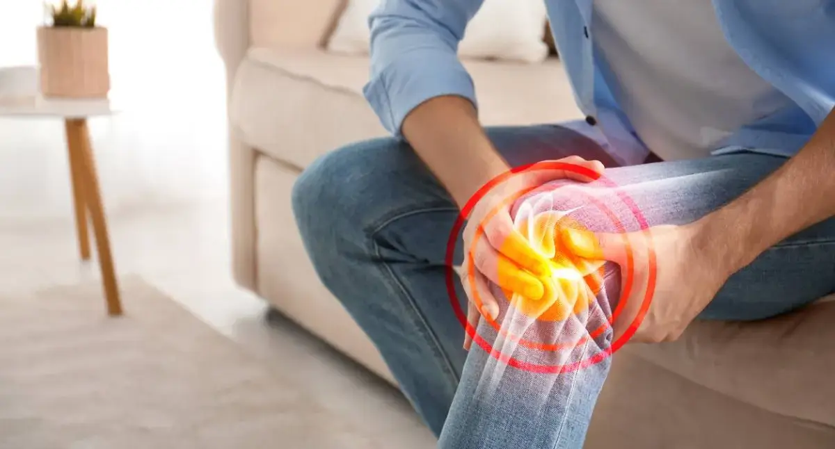 Adult holding a painful knee, a common site of osteoarthritis pain and stiffness