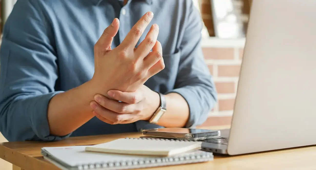 Person shaking out a numb, tingling hand at night, a common symptom of carpal tunnel syndrome