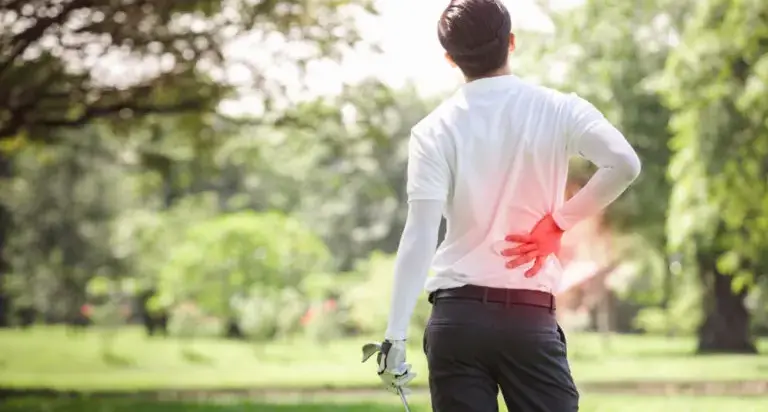 Adult holding their lower back in discomfort, representing overlooked spine injuries such as herniated discs and pinched