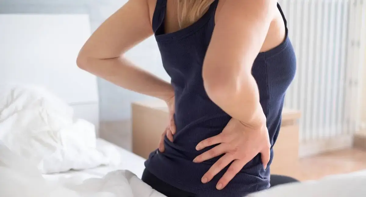 Side sleeper using a pillow between the knees and supportive head pillow to reduce sciatica pain at night