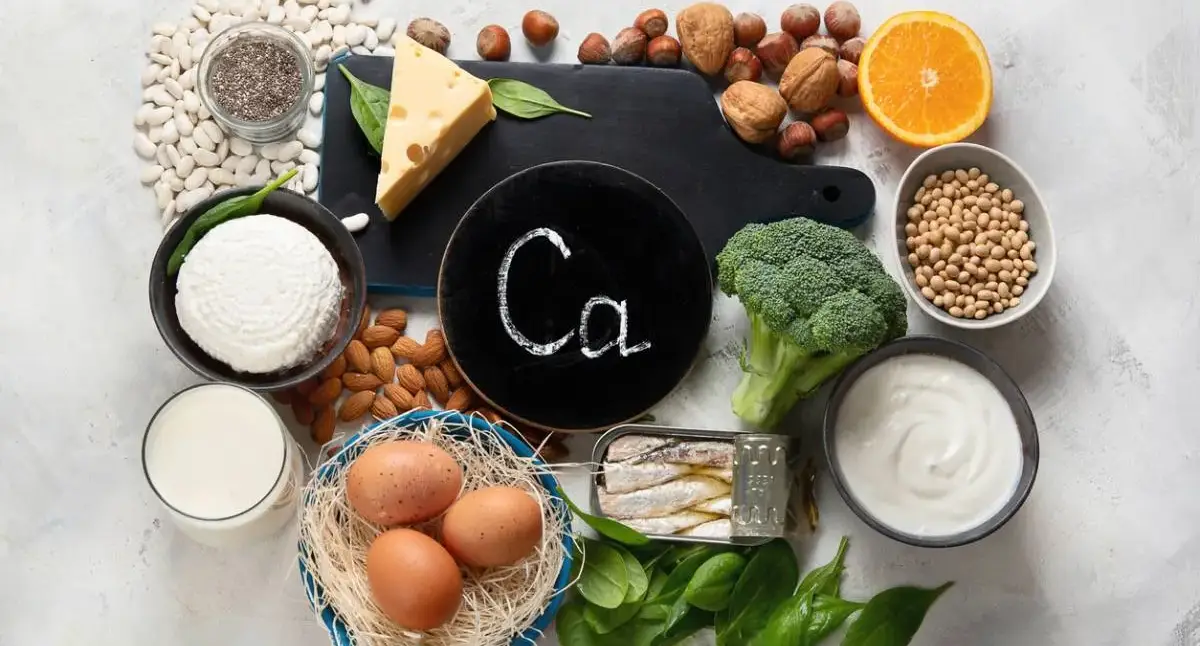 Spine-healthy foods on a kitchen counter, including leafy greens, salmon, yogurt, eggs, and citrus fruit