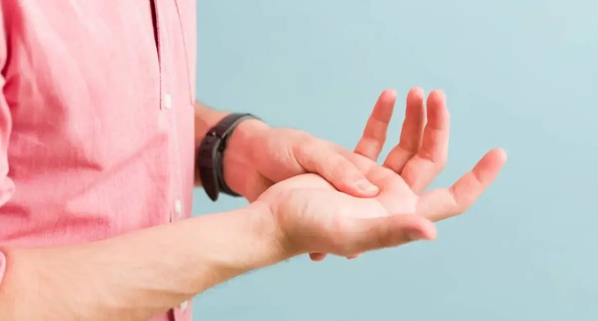 Person holding their wrist with numbness and tingling in the fingers, a common sign of carpal tunnel syndrome
