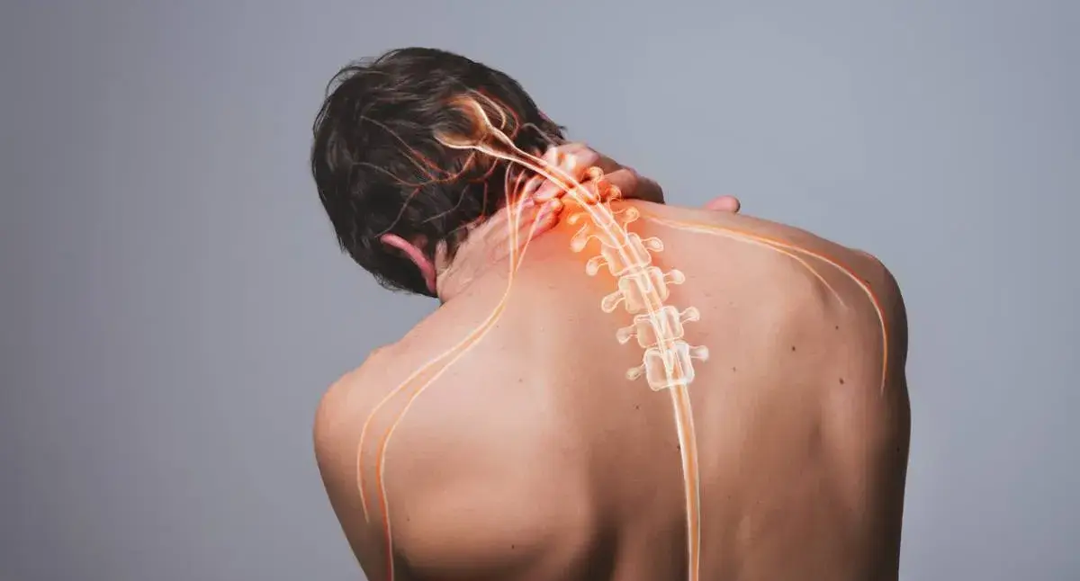 Adult holding the back of the neck while experiencing a headache, a possible sign of cervical nerve irritation