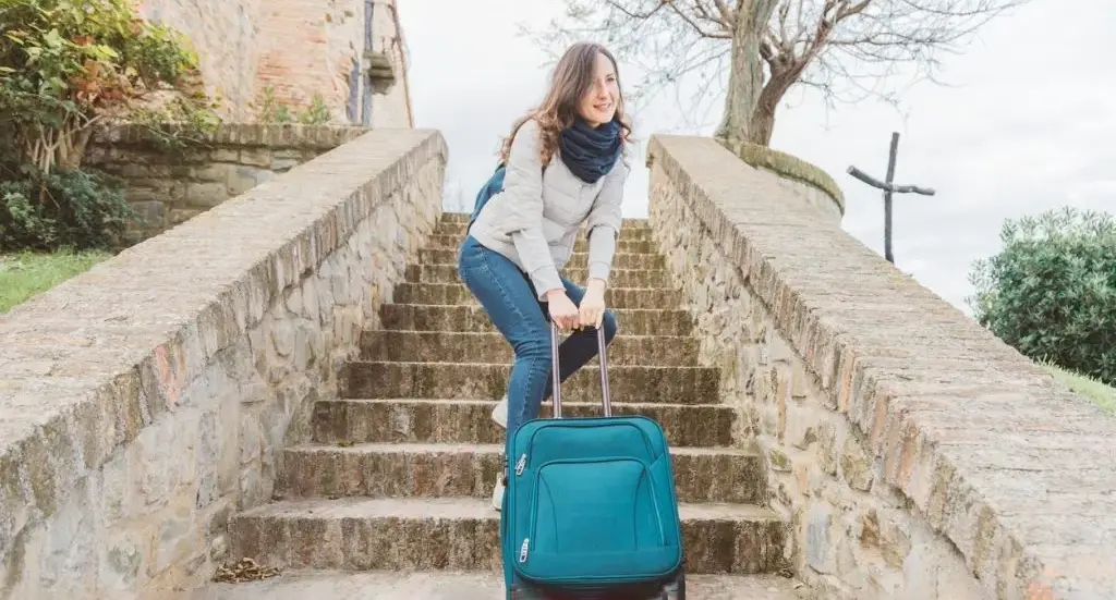 Traveler lifting a suitcase with knees bent and the bag close to the body to reduce back strain