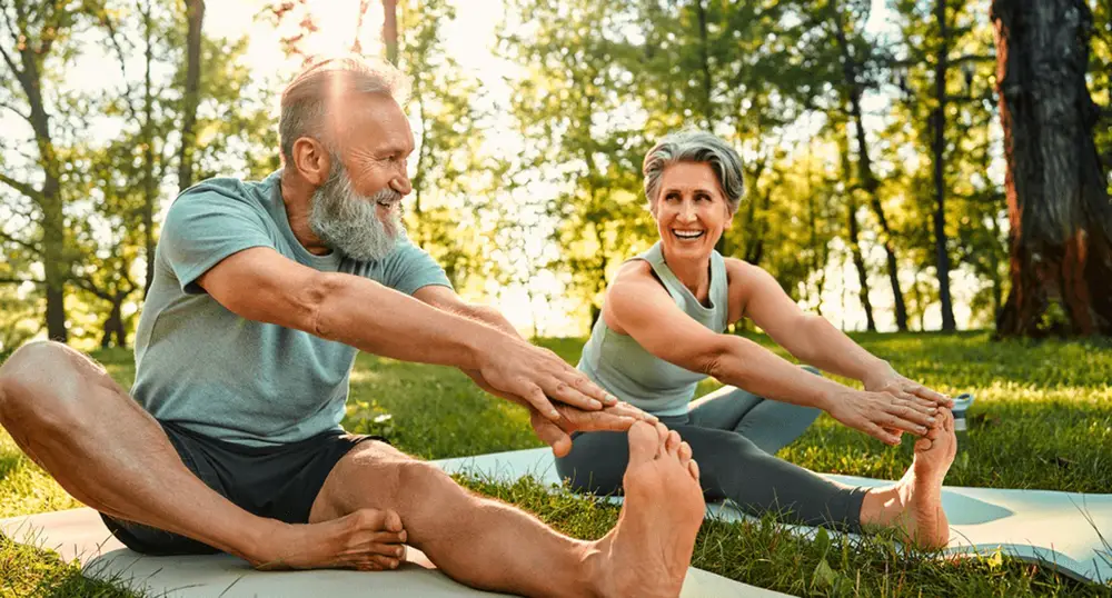 Active senior couple stretching together outdoors, highlighting improved flexibility after artificial disc replacement by the best spine surgeon in Los Angeles, CA.