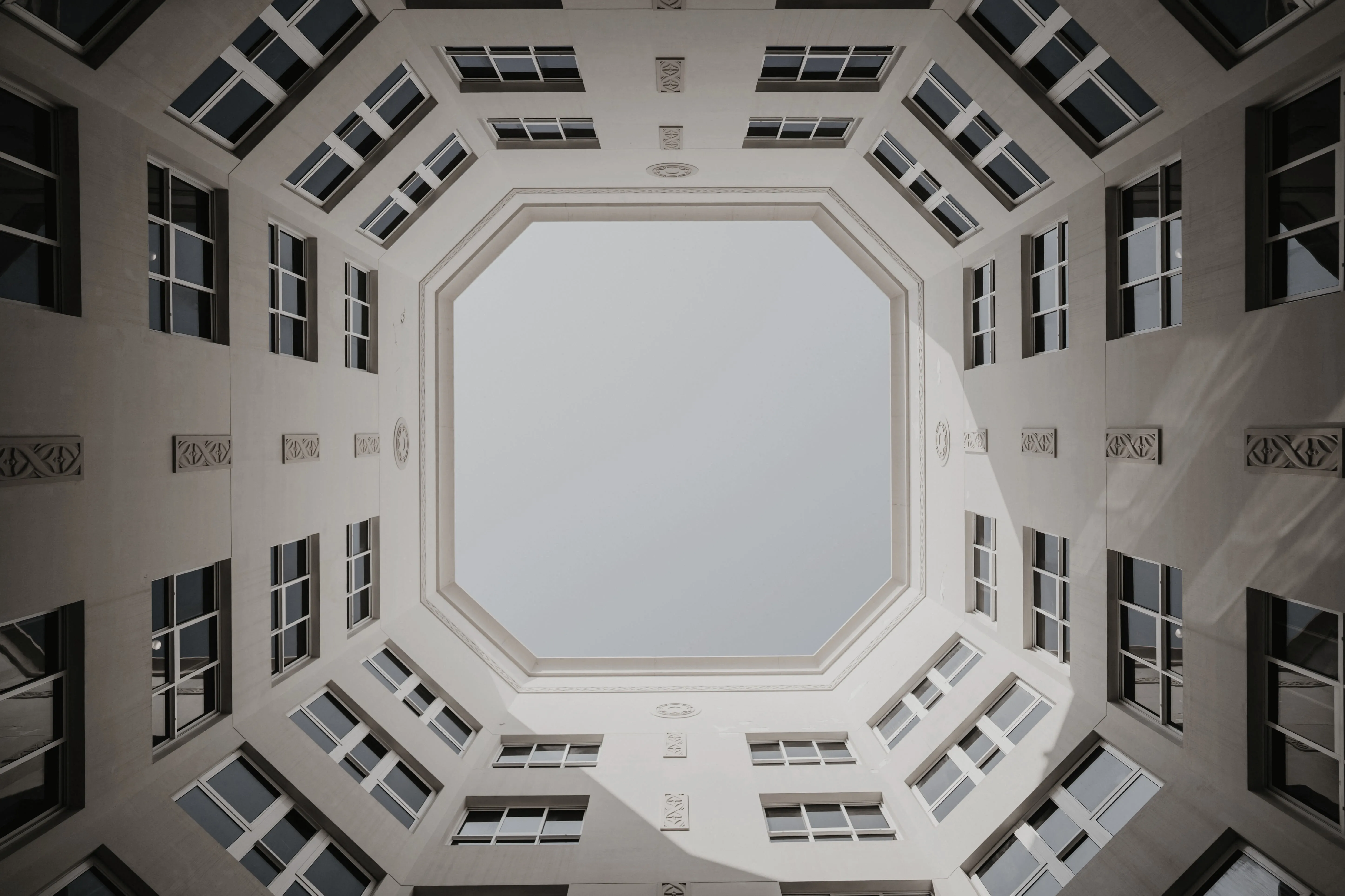 Interior view looking up inside an octagonal courtyard surrounded by multi-story building windows.